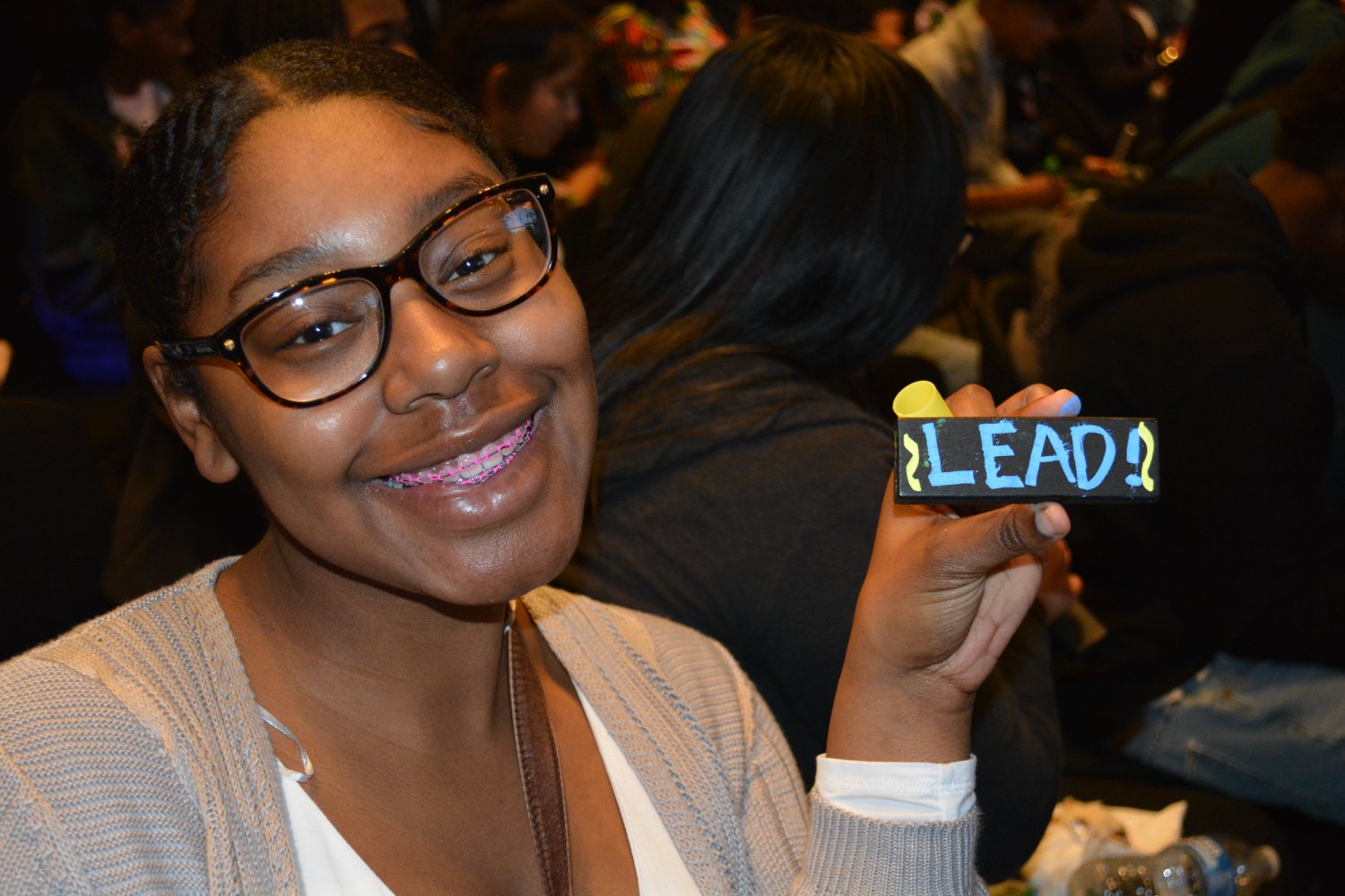 A young student holds up a "LEAD" brick during a SPEAK assembly